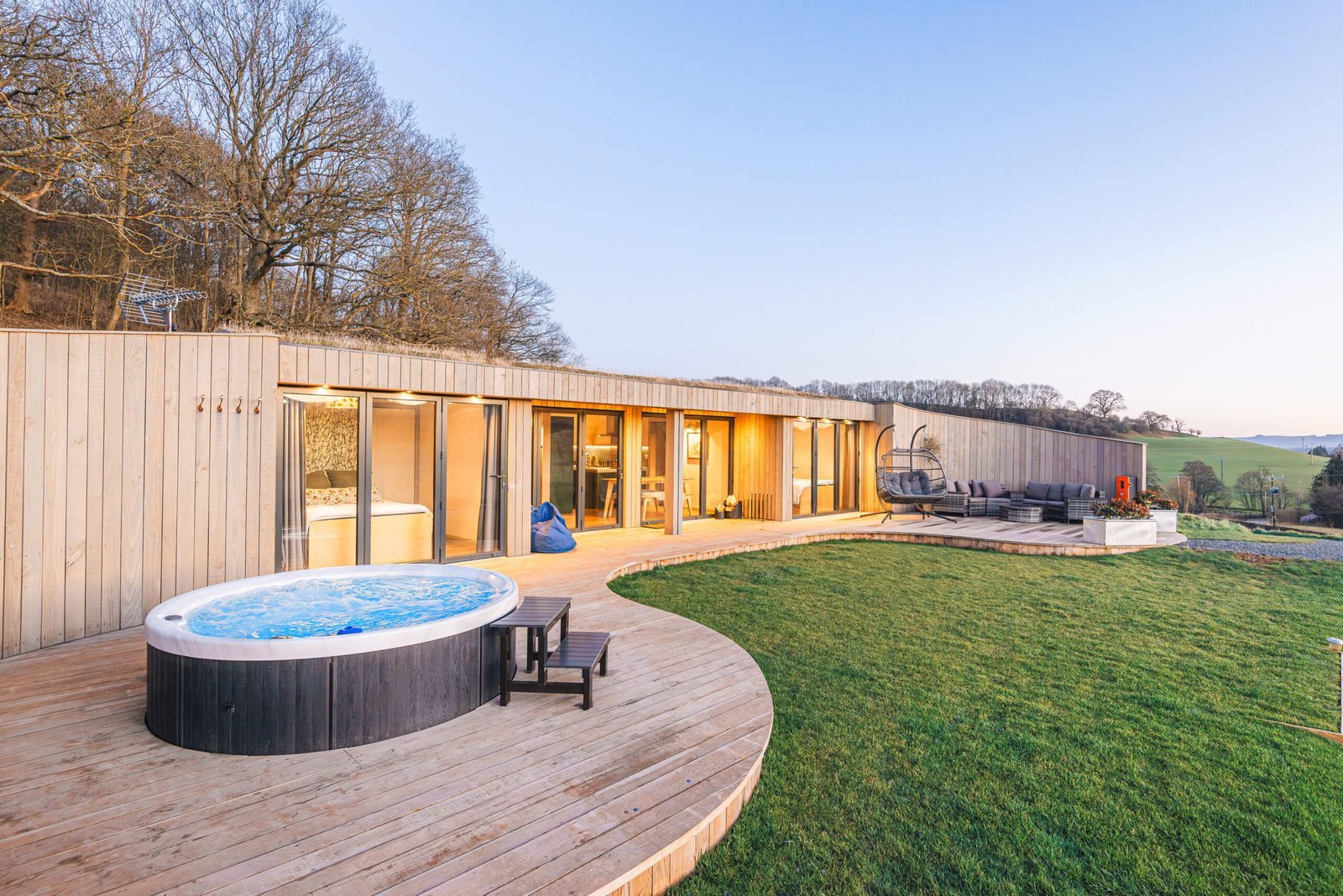 Pontypinna lodge exterior with a private hot tub and curved deck