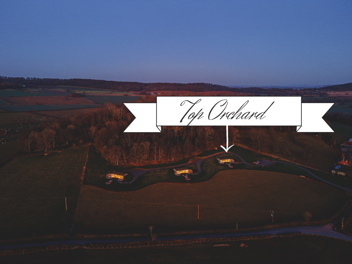 Aerial view of Lane End cabins at dusk, surrounded by countryside and highlighted with a banner.