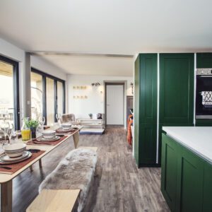 Spacious open-plan kitchen and dining area with green cabinets and a large table set for a meal.